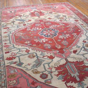 Traditional rug featuring a red central medallion and floral motifs on a cream field and wood floor.