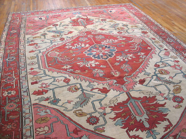 Traditional rug featuring a red central medallion and floral motifs on a cream field and wood floor.