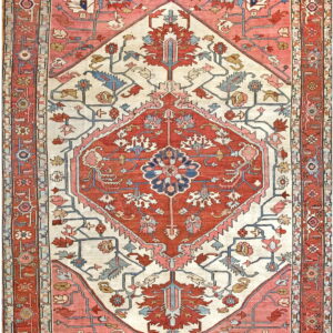 A low-pile rug with a large rust and coral geometric medallion centered on a cream colored field.