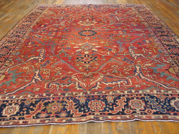 Large red rug featuring a complex blue and beige medallion pattern on wood flooring.