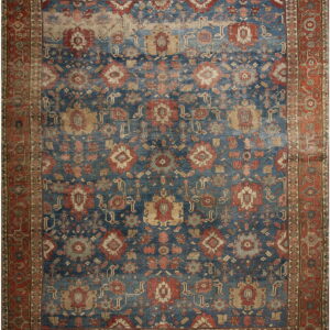 Distressed traditional rug with an indigo field, rust border, and all-over pattern in red, tan, and light gray.