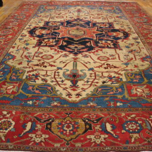 Traditional red, navy, and cream medallion rug lies on light wooden floors.