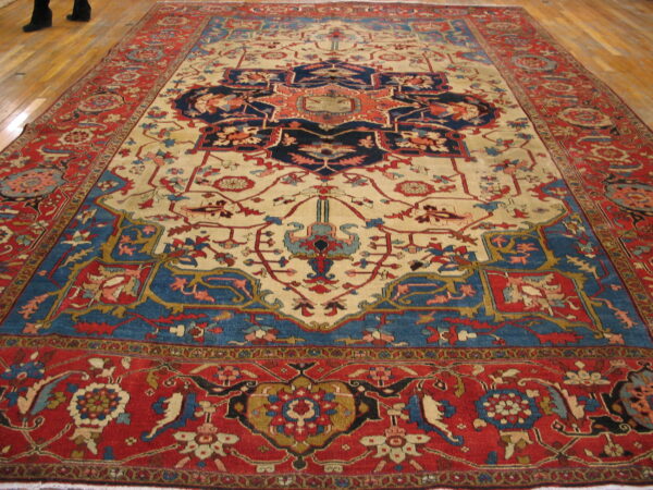 Traditional red, navy, and cream medallion rug lies on light wooden floors.