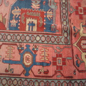 Geometric rug with deep blue, red, and beige tribal motifs on a muted pinkish-red field.