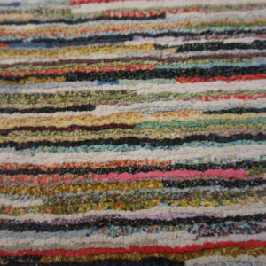 Detailed texture of a multicolor shag rug composed of thick horizontal bands in diverse bright colors.