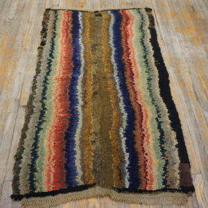 A runner rug with thick, colorful vertical stripes lies on a distressed wooden floor.