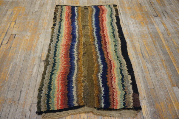 A runner rug with thick, colorful vertical stripes lies on a distressed wooden floor.