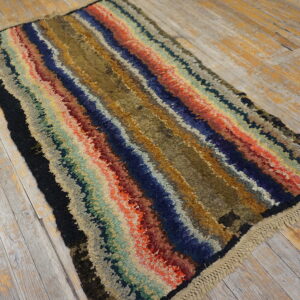 A multicolored, high-pile shaggy rug with wavy stripes rests on distressed wood flooring.