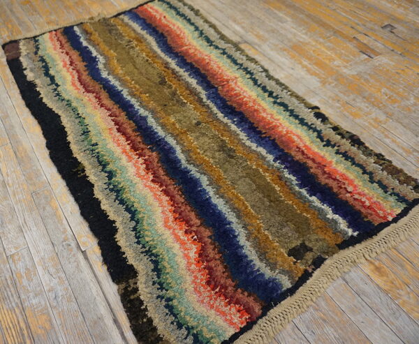 A multicolored, high-pile shaggy rug with wavy stripes rests on distressed wood flooring.