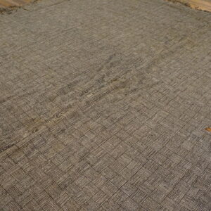 Brown flatwoven rug with a detailed basketweave texture resting on dark hardwood flooring.