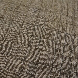 Close-up view of a low-pile rug showing a striped, two-tone brown basketweave design and fringed edge.