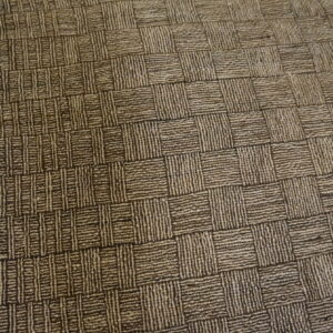 Textured brown and beige rug with a square grid pattern rests on a wooden floor.