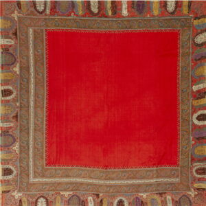 A vibrant red rug with elaborate, multicolored paisley and shield-like decorative borders.