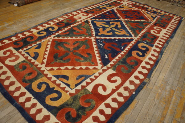 Red, blue, yellow, and cream rug with bold geometric tribal motifs lying on light, worn wood floors.