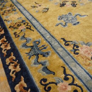 Golden yellow high-pile rug detail showing blue, pink, and brown traditional patterns and wood flooring.
