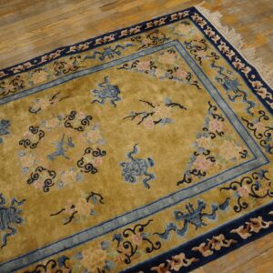 Mustard gold high-pile rug with navy and pale blue borders and scattered floral patterns on distressed wooden floors.