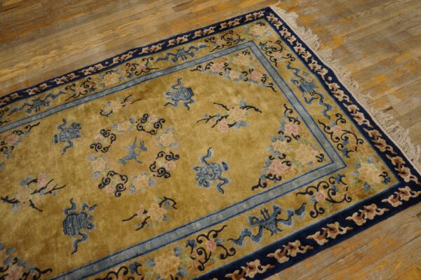 Mustard gold high-pile rug with navy and pale blue borders and scattered floral patterns on distressed wooden floors.