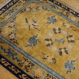 Plush gold rug with navy and light blue borders, featuring pink and blue floral motifs on wood flooring.
