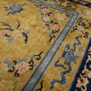 Gold rug with pink, light blue, and dark blue traditional floral motifs and ornate multiple borders.