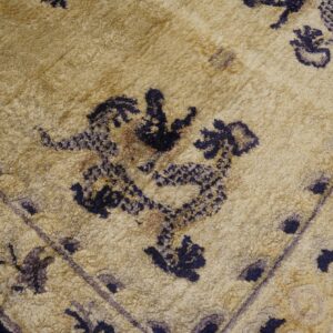 Textured beige rug featuring dark blue stylized dragon patterns and faded purple border details.