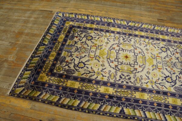 Medium pile cream and navy rug featuring traditional patterns sits on rustic, wide plank wood flooring.