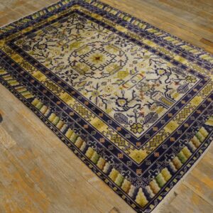 Geometric rug in cream, navy, and olive green on distressed light brown wooden flooring.
