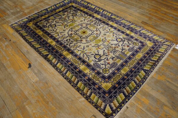 Geometric rug in cream, navy, and olive green on distressed light brown wooden flooring.