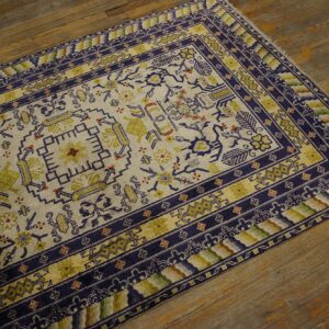 Cream rug featuring geometric and floral designs in deep blue and chartreuse colors on wood planks.