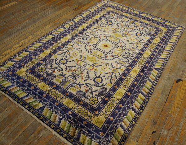 Cream rug with indigo and gold geometric patterns and multi-colored borders lying on distressed wood.