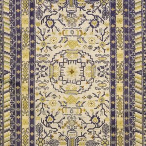 Ornate low-pile rug featuring complex geometric borders and designs in cream, deep purple, and pale yellow.