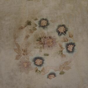 Distressed beige rug featuring an antique-style floral wreath design in muted blues, mauves, and tans.