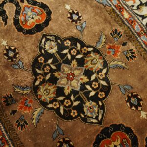 Detailed view of a warm brown rug with complex floral motifs and border elements in black, blue, and orange.