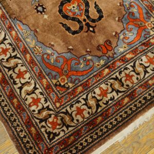 Ornate brown, blue, and orange patterned rug corner featuring complex traditional motifs over rustic wood flooring.