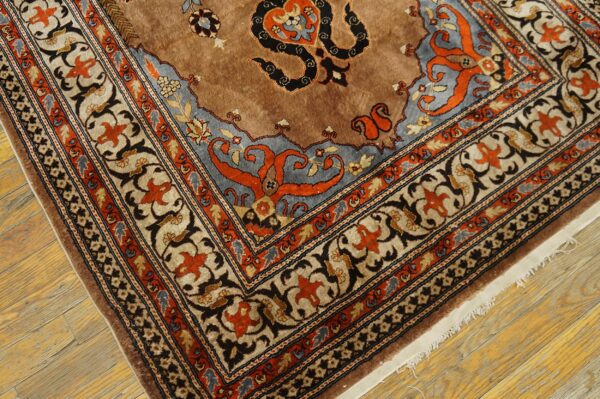 Ornate brown, blue, and orange patterned rug corner featuring complex traditional motifs over rustic wood flooring.