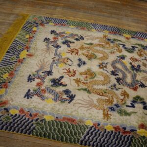 Cream rug featuring golden and blue dragons, a colorful patterned border, and yellow fringe on rustic wood planks.