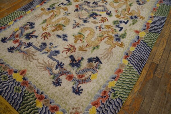Ornate rug with gold and blue dragons, a complex wave border, resting on dark hardwood floors.