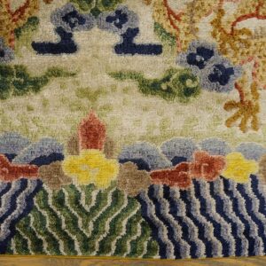 Textured cream rug featuring gold motifs, blue flowers, and a detailed border of wavy blue water and green plants.