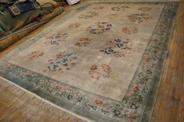 Vintage light cream color european influenced florals luxurious silk pile chinese room size rug 3 Beige area rug with scattered colorful floral clusters and a wide green border on distressed hardwood floors.