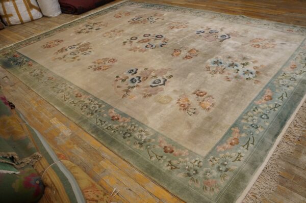Vintage light cream color european influenced florals luxurious silk pile chinese room size rug 2 Beige rug with scattered pastel floral motifs and a wide sage green border on rustic wood flooring.