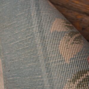 Rolled blue and light beige low-pile rug detail showing a ribbed texture against rustic wood planks.