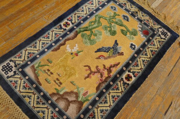 High-pile yellow rug displaying a deer, bird, and vine motif with complex indigo blue outer borders.