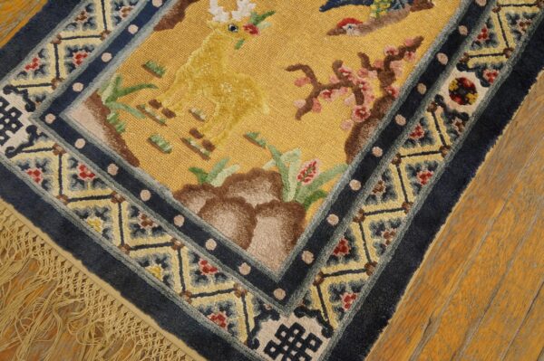Gold scenic rug with deer and flowers, outlined by plush navy and patterned light blue borders.