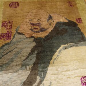 Textured brown and olive rug featuring a large laughing figure motif and purple square seals on wood floor.