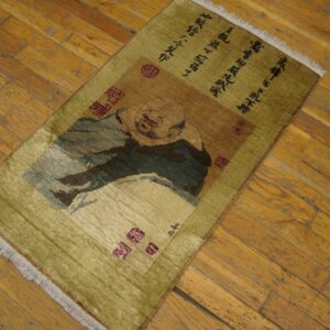 A chartreuse rug featuring a smiling figure design and calligraphy rests on distressed wood planks.