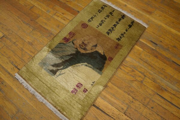 A chartreuse rug featuring a smiling figure design and calligraphy rests on distressed wood planks.