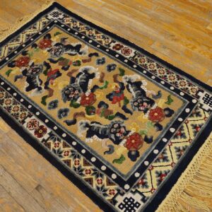 Gold rug with stylized dark blue animal patterns, multicolor florals, and navy borders rests on a distressed wooden floor.