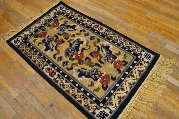 Gold rug with stylized dark blue animal patterns, multicolor florals, and navy borders rests on a distressed wooden floor.