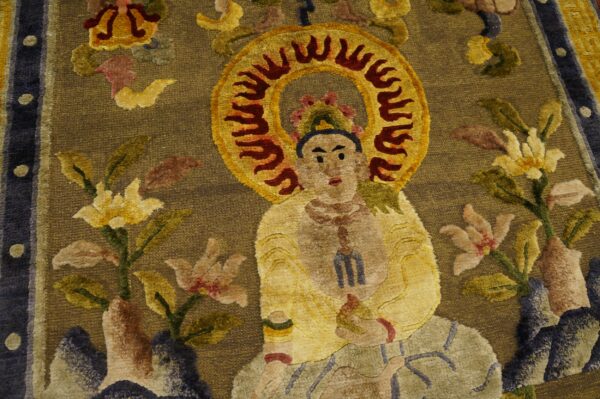 Detailed view of a rug with a seated figure and flaming halo on a textured brown-gold field surrounded by multicolor florals.