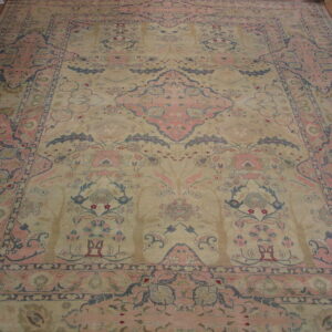 Muted beige, pink, and blue ornate rug featuring a central medallion on wide plank wood flooring.