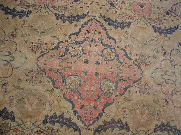 Faded low-pile rug showing a pink central medallion and blue scrolling florals on a light beige field.